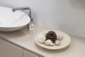 close up view of shelf in bathroom with decor in form of dish with cone and shells and white ceramic sink with chrome tap