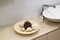 close up view of shelf in bathroom with decor in form of dish with cone and shells and white ceramic sink with chrome tap Royalty Free Stock Photo