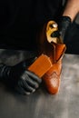 Close-up view of shoemaker in black gloves polishing light brown leather shoes with brush during restoration working. Royalty Free Stock Photo