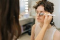 Close-up view from shoulder of unrecognizable female make-up artist applying highlighter for face sculpting of pretty Royalty Free Stock Photo