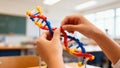 Hands assembling a colorful DNA model in a classroom setting Royalty Free Stock Photo