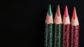 A close-up view shows a sharpened colored pencil, striped in red and green, making a red stroke on a background that is black Royalty Free Stock Photo