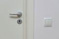 Close up view of silver door handle and  white light switch isolated. Building construction elements concept Royalty Free Stock Photo