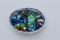 Close up view of a silver metal bowl containing decorative glass stones