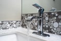 Close up view of a sink faucet inside an upscale bathroom, the water currently running from the tap Royalty Free Stock Photo