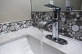 Close up view of a sink faucet inside an upscale bathroom, the water currently running from the tap Royalty Free Stock Photo