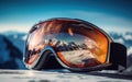 Close-up view of ski goggles against a mountainous area full of snow with a beautiful red reflection of the landscape.