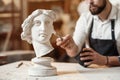 Skillful sculptor makes professional restauration of gypsum sculpture of woman`s head at the creative workshop. Royalty Free Stock Photo