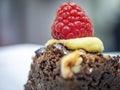 Close-up view of a slice of a dark fruit cake with a raspberry