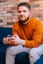 Close-up view of smiling handsome bearded young man holding controllers and playing video games on console Royalty Free Stock Photo