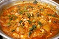 Close-up view of a spicy and hot cuisine with various sea food ingredients such as shrimp, small octopus, and tripe