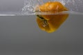 Close up view splashing water and falling yellow pepper. Royalty Free Stock Photo