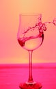 Close up view of splashing water in glass . Pink background. Royalty Free Stock Photo