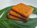 Close up view of a stack of crackers biscuit on an ornamental green monstera leaf.