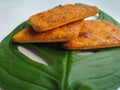 Close up view of a stack of crackers biscuit on an ornamental green monstera leaf.