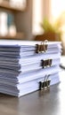 Close up view of a stack of white paper documents held together with binder clips on a wooden desk Royalty Free Stock Photo