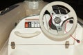 A close-up view of the steering wheel of a small white rubber motorboat with cockpit and control buttons