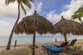 Close-up view of sun loungers with sun umbrellas on white sandy beach of Aruba island in Atlantic Ocean. Royalty Free Stock Photo