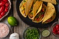 Close-up view of tasty street tacos with beef, tomatoes, onion and cheese on black round plate. Ingredients for cooking tacos on Royalty Free Stock Photo