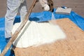 Close up view of technician dressed in a protective white uniform spraying foam insulation using Plural Component Spray Gun.