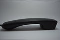 A black plastic handset from a landline phone without buttons is located on a white background. Royalty Free Stock Photo
