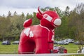 Close up view of temporary outdoor parking place for event. Huge inflated plastic ARLA red cow figure.