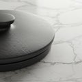 A close-up view of a textured black circular object, possibly a lid, resting on a smooth Royalty Free Stock Photo