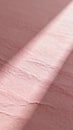 A close-up view of a textured pink surface illuminated by a diagonal beam of light highlighting subtle ridges and shadows Royalty Free Stock Photo