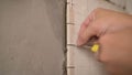 Close-up view of tiler hands fixing wall tile with spacers at home repair renovation work. Laying tiles on the wall Royalty Free Stock Photo