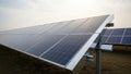 Close up view of a solar panel array tilted on metal frames in an outdoor field with dry grass and a bright sky in the background Royalty Free Stock Photo