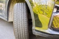 Close up view of tire and reflection view of green field and green bushes in black car bumper