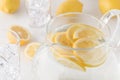 A Close Up View Of The Top Of A Pitcher Filled With Lemon Water And Slices Of Lemon Surrounded By Glasses Of Ice.