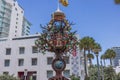 Close up view of tree-shaped statue with lock, set against backdrop of charming buildings on Collins Avenue in Miami