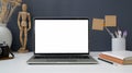 Close up view of workspace with open blank screen laptop, painting tools and office supplies on white table with grey wall Royalty Free Stock Photo