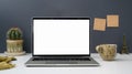 Close up view of workspace with open blank screen laptop, cup, sticky note and decorations on white table with grey wall Royalty Free Stock Photo