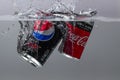 Close up view of two cans falling in water. Coca cola vs pepsi cola