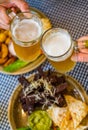 Two glass of beer in hand. Beer glasses clinking in bar or pub on table with food background Royalty Free Stock Photo