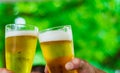 Two glass of beer in hand. Beer glasses clinking at outdoor bar or pub Royalty Free Stock Photo