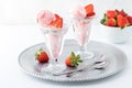 Close up view of two glass dessert dishes filled with strawberry ice cream with a bowl of strawberries in behind. Royalty Free Stock Photo