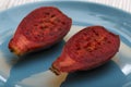Close up view of two halves of a red indian fig also called prickly pear on a blue plate