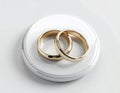 Two Gold Wedding Rings Interlocked on a White Glossy Round Surface gold rings interlocking rings Royalty Free Stock Photo