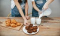 Close up view of two little girls in blue chef uniform that pouring milk into glasses on the kitchen with cookies on Royalty Free Stock Photo