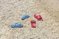 Close up view of two pairs of beach flip flops on sand isolated.