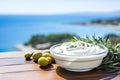 Close up view of tzatziki on Greek table, sea in background