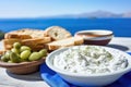 Close up view of tzatziki on Greek table, sea in background