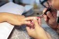 Close-up of manicurist applying red nail polish