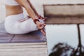 close up view of unrecognizable young asian woman doing yoga in a park. Sitting on the bridge with reflection on the water lake.