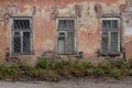 Close-up view of the facade of an old abandoned house. Three windows with lattice, shabby plastered brick walls Royalty Free Stock Photo