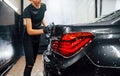 Close up view of vehicle getting wiped. Modern black automobile get cleaned by woman inside of car wash station Royalty Free Stock Photo