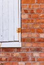 Close-up view of a vintage red brick wall with a partially open window shutter